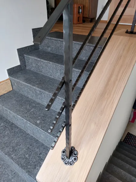 Geländerpfosten mit dekorativer Fußplatte an einer Steintreppe