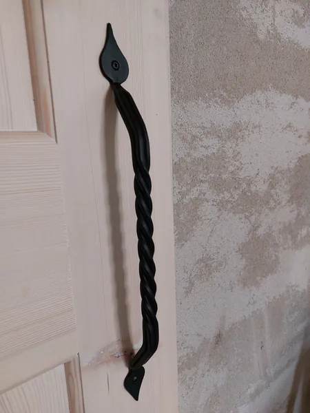 Geschmiedeter Griff mit gedrehtem Bügel an einer Holztür