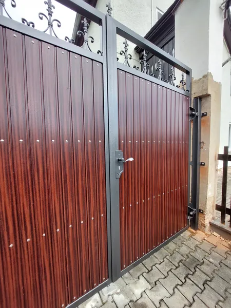 Hoftor mit roten Holzfüllungen und geschmiedeten Ornamenten