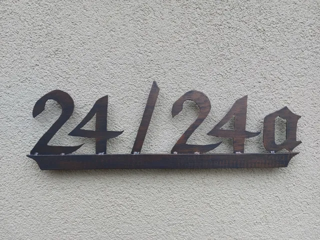 Metallene Hausnummern an einer hellen Wand