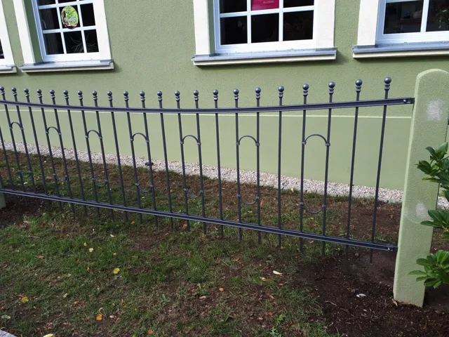 Metallzaun entlang einer Hausfassade
