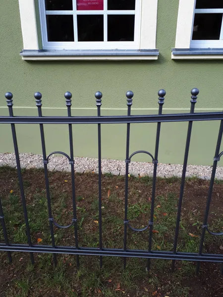 Metallzaun entlang einer Hausfassade