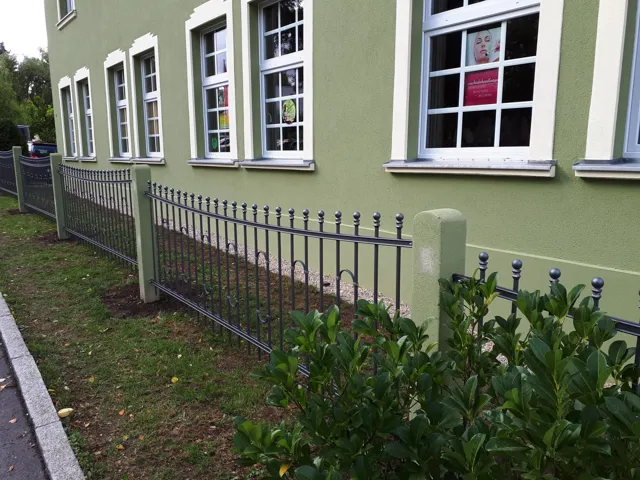 Metallzaun entlang einer Hausfassade