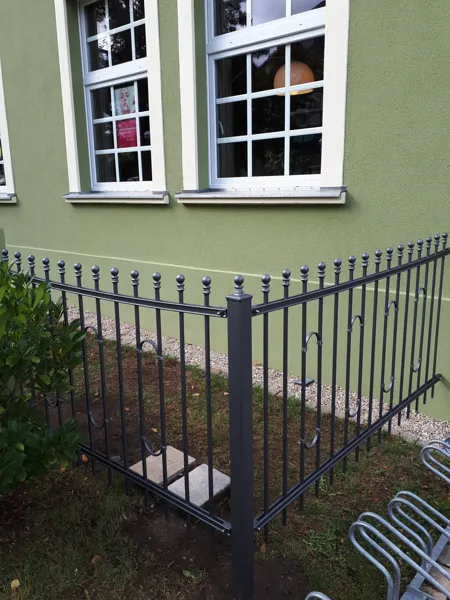 Metallzaun entlang einer Hausfassade