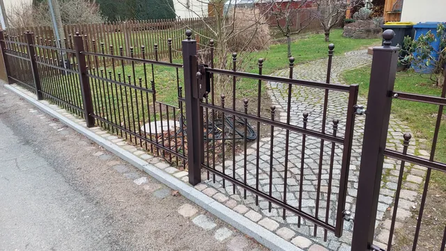 Metallzaun mit kleinen Zugangstüren und dekorativen Pfosten