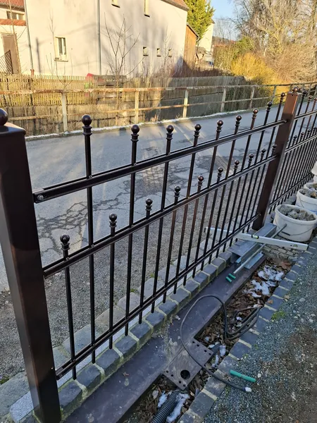 Metallzaun mit Zierspitzen entlang einer Grundstücksgrenze
