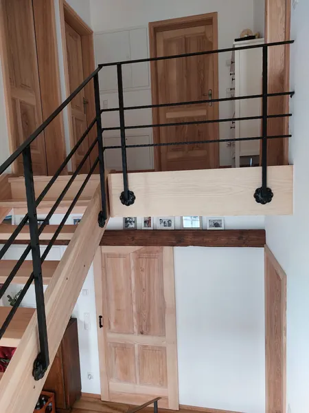 Podestgeländer aus Metall über einer offenen Holztreppe