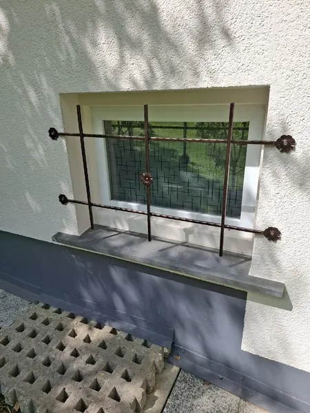 Schlichtes Fenstergitter mit waagerechten Stäben an einer Fassade