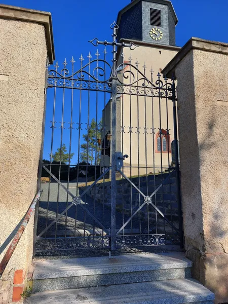 Schmiedeeisernes Tor zwischen gemauerten Pfeilern