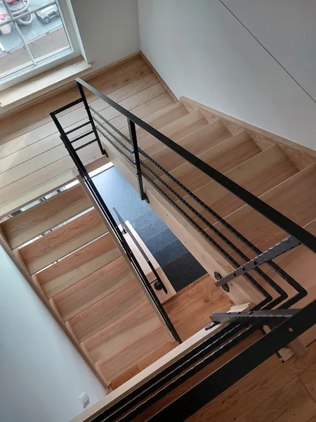 Schwarzes Geländer am oberen Absatz einer Holztreppe