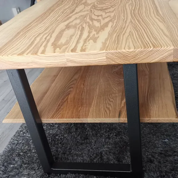Schwarzes Tischgestell unter einer gemaserten Holzplatte