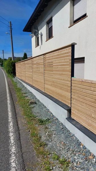 Sichtschutzzaun mit Holzfüllungen und dunklen Metallpfosten