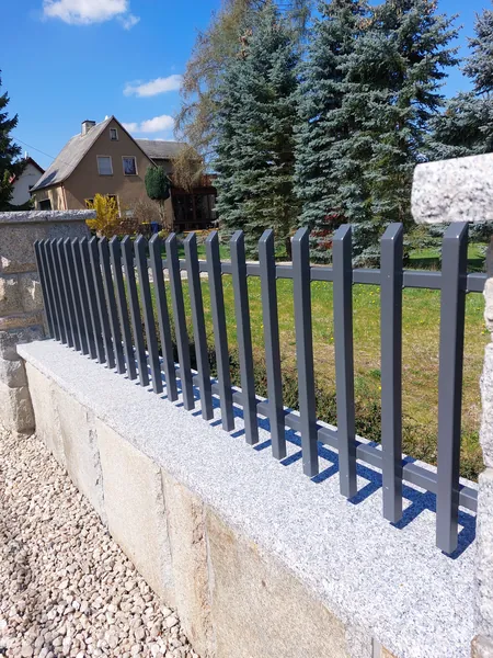 Zaunelement mit Stäben auf einer Natursteinmauer