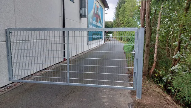 Zweiflügeliges Gittertor an einem gepflasterten Durchgang